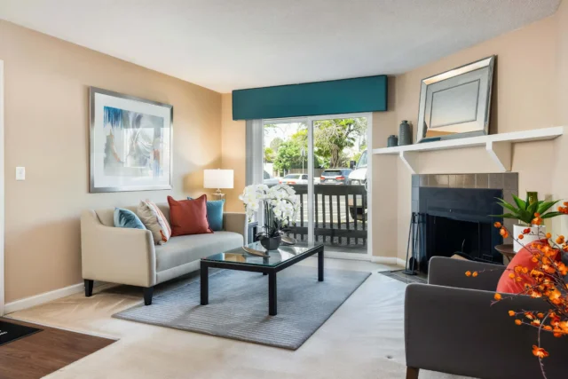Bright Oak Ridge Apartments living room with wood-burning fireplace and private balcony in Aurora